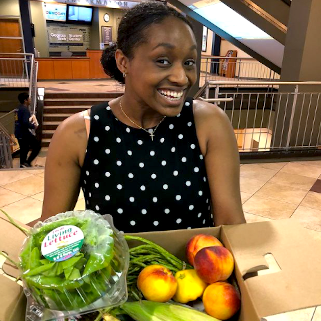 Person smiling while holding fruits & vegetables