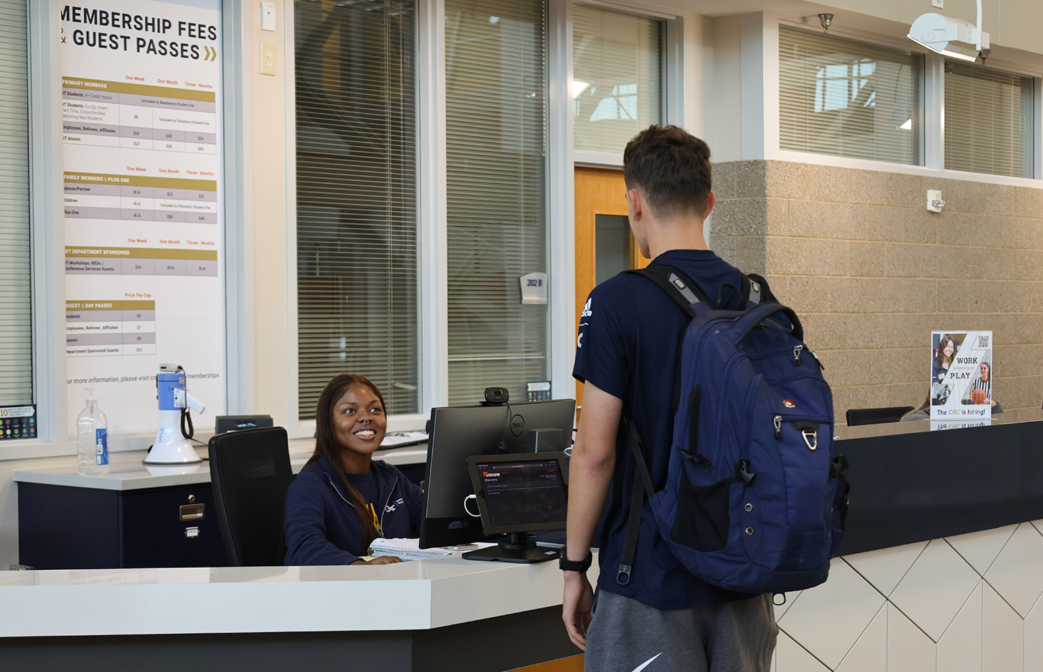 CRC student staff sitting at the membership desk while a client requests information.