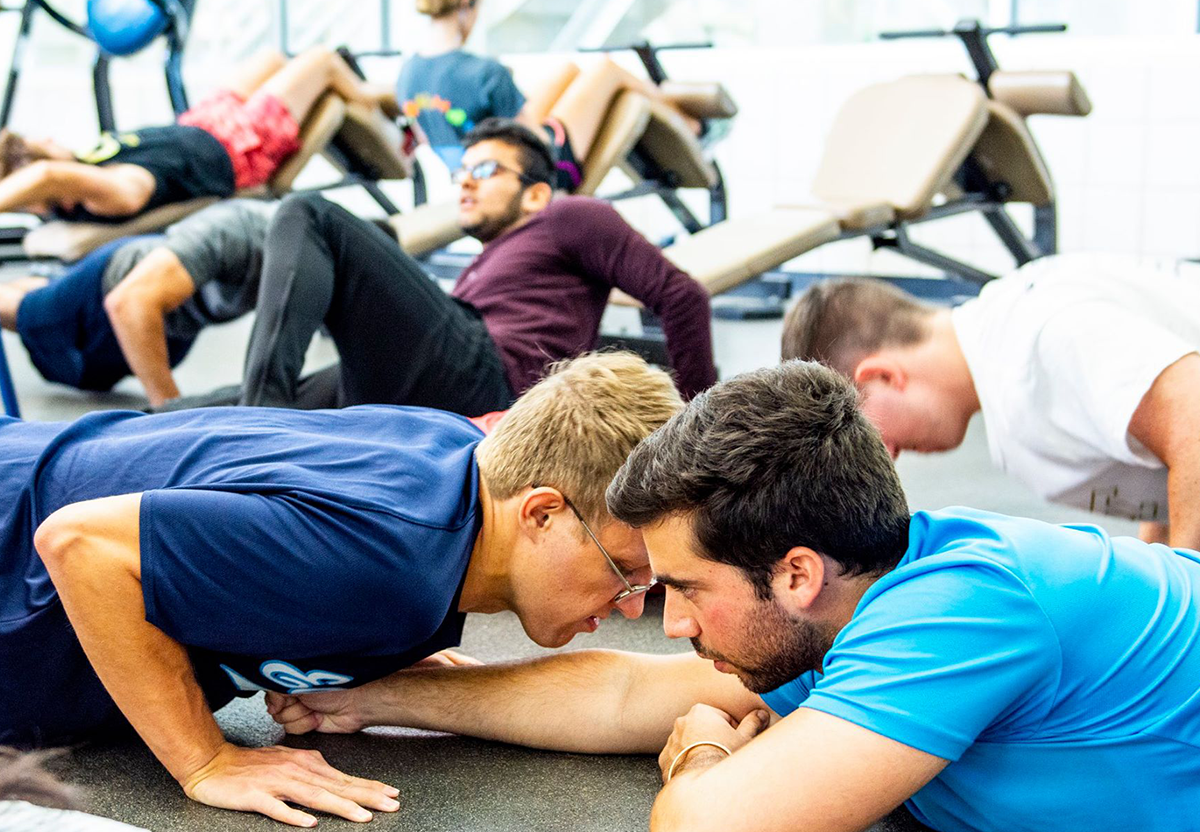 A guy with a coach doing push ups.