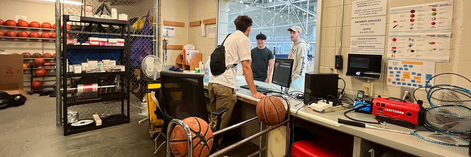 A CRC student staff inside the Equipment Issue space speaks with two clients.