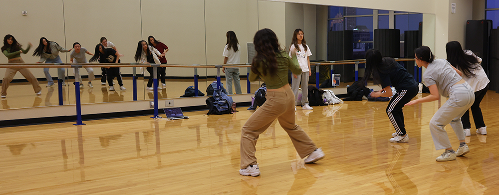 A group of young women dancing in front of a mirror.